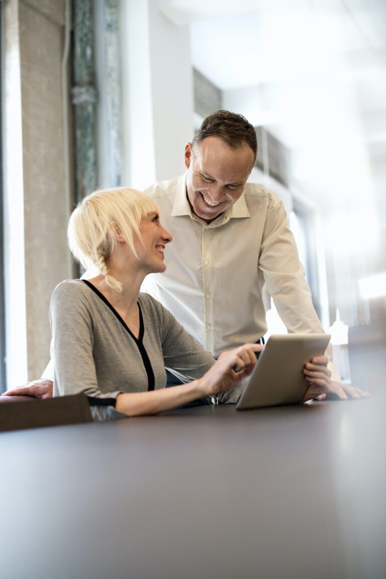 Office life. Two people sharing a digital table in an office.